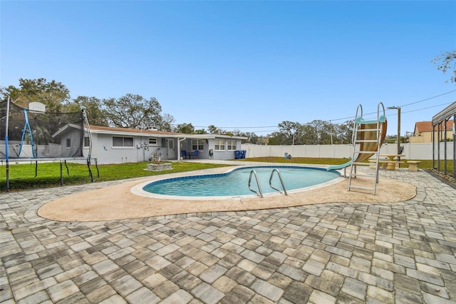 view of pool featuring a water slide, a trampoline, and a patio area