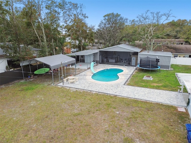 view of pool with a carport, a water slide, a trampoline, a lawn, and a shed