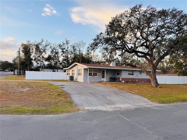 ranch-style house featuring central AC unit and a lawn