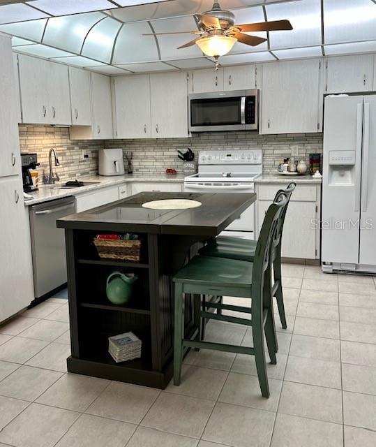 kitchen featuring tasteful backsplash, sink, light tile patterned floors, and appliances with stainless steel finishes