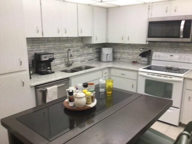 kitchen featuring sink, decorative backsplash, stainless steel appliances, and white cabinets