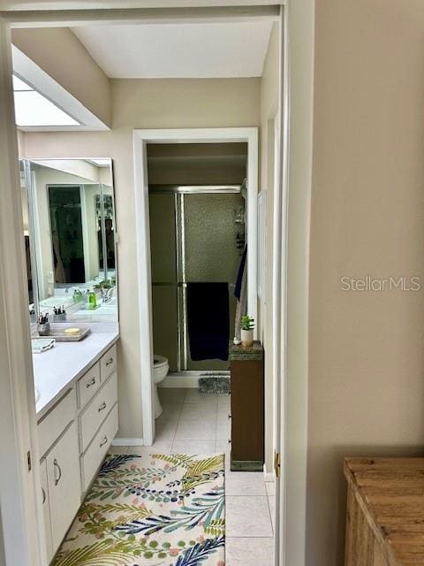 bathroom with tile patterned floors, toilet, a shower with shower door, and vanity