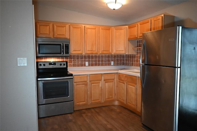 kitchen featuring light brown cabinetry, backsplash, dark hardwood / wood-style floors, lofted ceiling, and stainless steel appliances