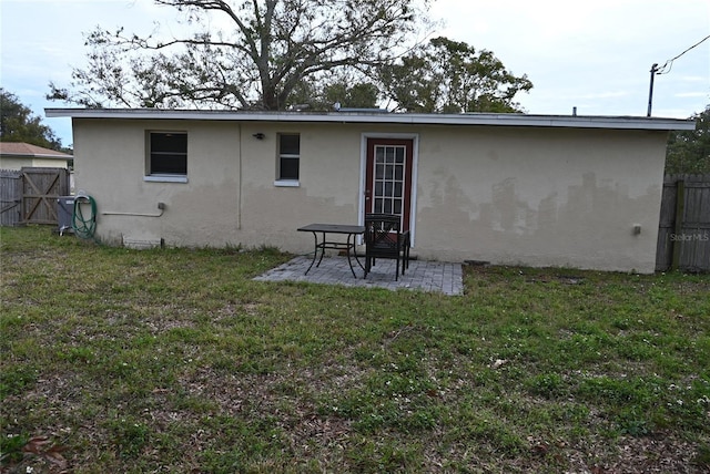 back of property with a patio area and a lawn