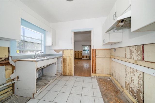 kitchen with wood walls, a wealth of natural light, sink, and white cabinets