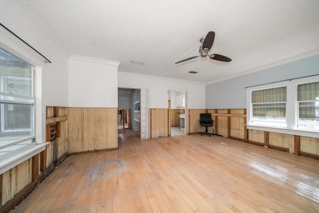 unfurnished living room with hardwood / wood-style floors, crown molding, a wealth of natural light, and ceiling fan