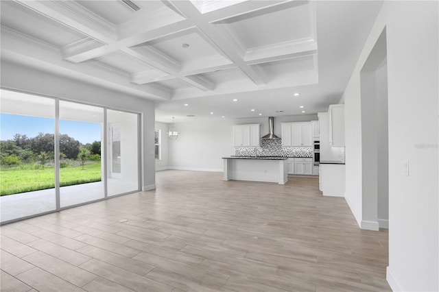 unfurnished living room featuring beamed ceiling, coffered ceiling, and light hardwood / wood-style flooring