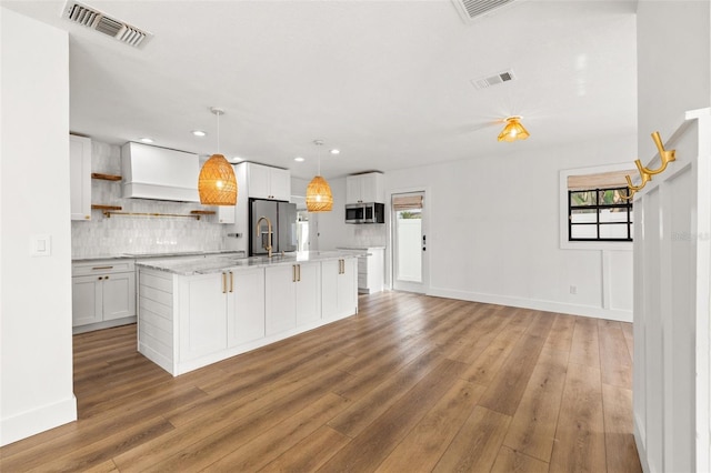 kitchen featuring white cabinetry, a wealth of natural light, custom range hood, and appliances with stainless steel finishes