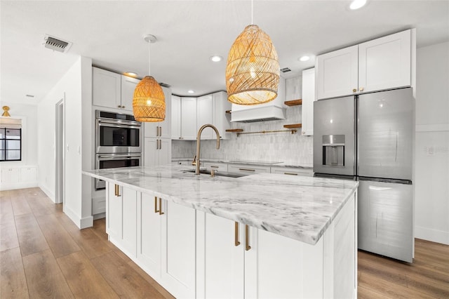 kitchen with sink, light stone countertops, white cabinets, and appliances with stainless steel finishes