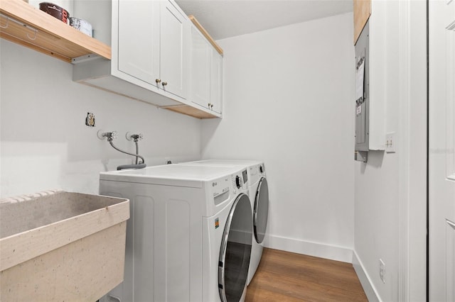 washroom with sink, hardwood / wood-style flooring, cabinets, and washing machine and clothes dryer