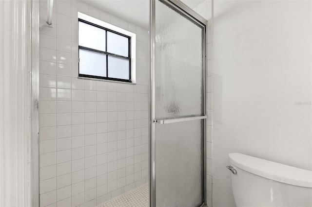 bathroom featuring a shower with door and toilet