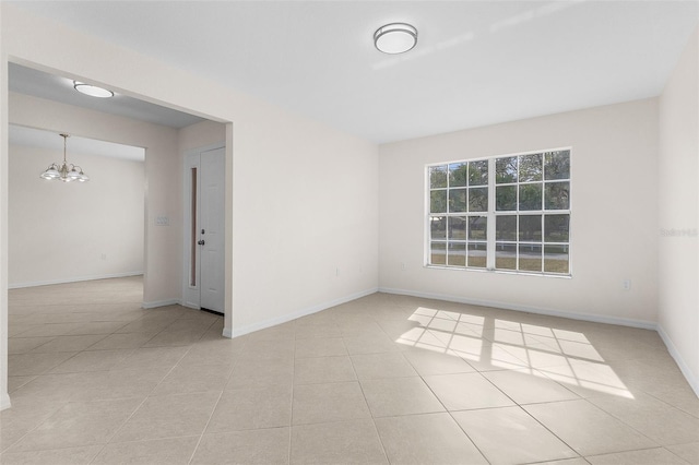 tiled empty room featuring a chandelier