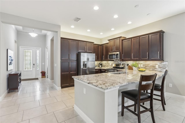 kitchen featuring sink, appliances with stainless steel finishes, light stone counters, light tile patterned flooring, and kitchen peninsula