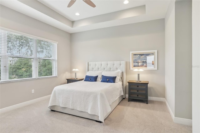 carpeted bedroom featuring a tray ceiling and ceiling fan