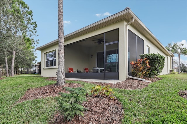 back of house featuring a lawn, a sunroom, and ceiling fan