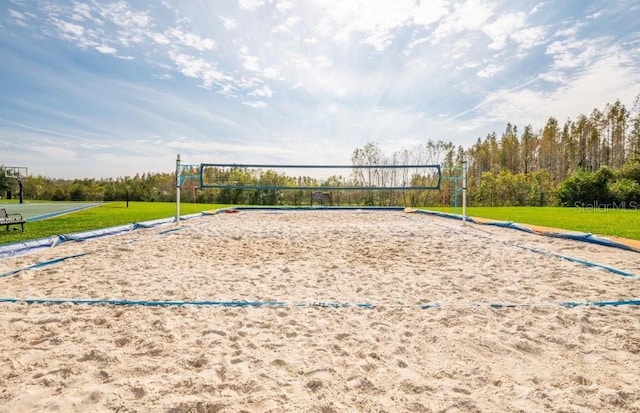 view of community with volleyball court and a lawn