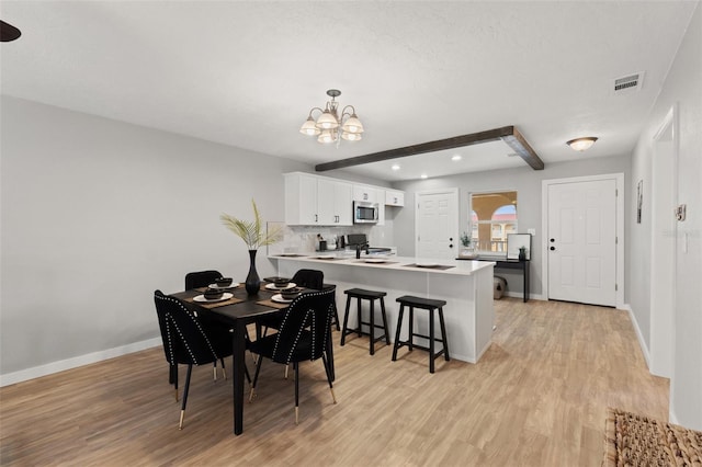 dining room featuring sink, beam ceiling, light hardwood / wood-style floors, and a notable chandelier