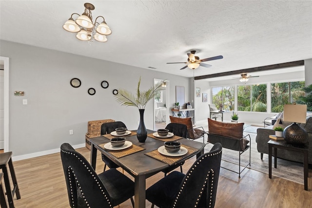 dining area with ceiling fan with notable chandelier, a textured ceiling, and light wood-type flooring