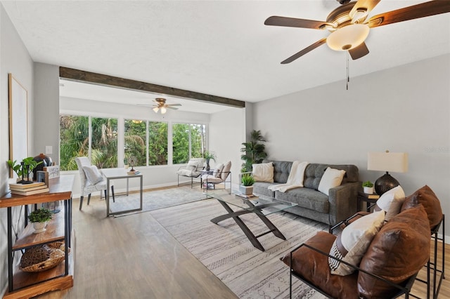 living room featuring ceiling fan, beamed ceiling, and light hardwood / wood-style floors