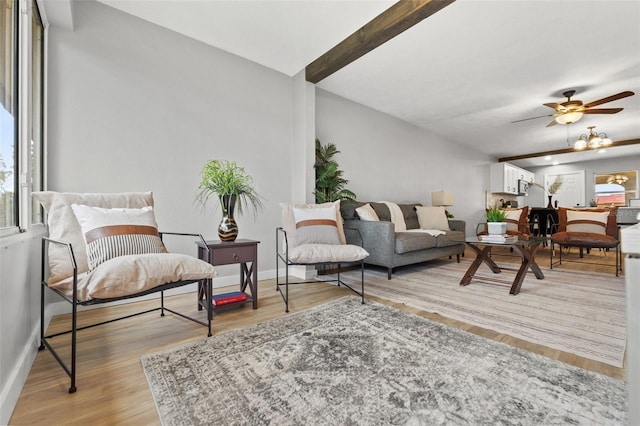 living room with ceiling fan, light wood-type flooring, plenty of natural light, and beamed ceiling