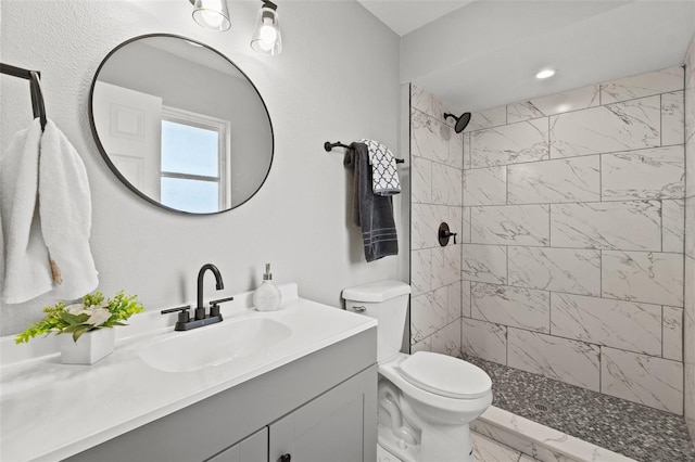 bathroom with toilet, vanity, and tiled shower