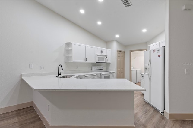 kitchen featuring sink, separate washer and dryer, kitchen peninsula, white appliances, and white cabinets