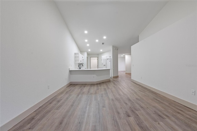 unfurnished living room featuring sink and light hardwood / wood-style flooring