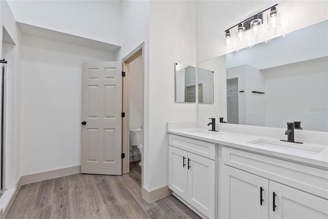 bathroom featuring vanity, an enclosed shower, wood-type flooring, and toilet