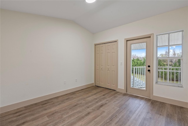 interior space with access to exterior, vaulted ceiling, and light hardwood / wood-style floors