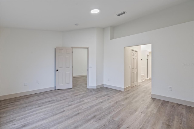 empty room featuring baseboards, visible vents, lofted ceiling, and light wood finished floors