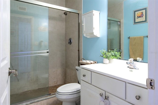 bathroom featuring toilet, a shower with shower door, and vanity