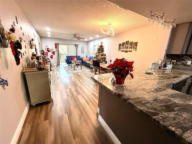 kitchen featuring a textured ceiling, ceiling fan, and stone counters