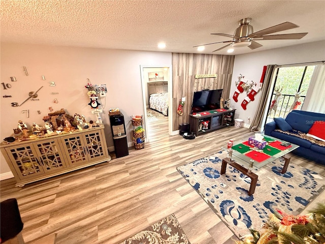 living room with ceiling fan, light hardwood / wood-style flooring, and a textured ceiling