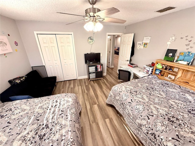 bedroom with a closet, ceiling fan, light hardwood / wood-style floors, and a textured ceiling