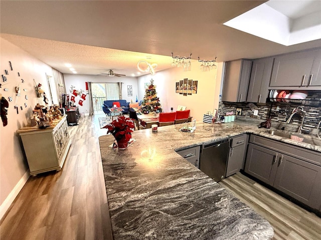 kitchen featuring ceiling fan, gray cabinetry, sink, dishwashing machine, and backsplash