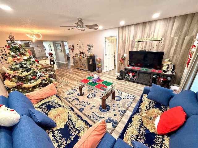 living room featuring ceiling fan, wood-type flooring, and a textured ceiling