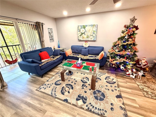 living room featuring ceiling fan, hardwood / wood-style floors, and a textured ceiling