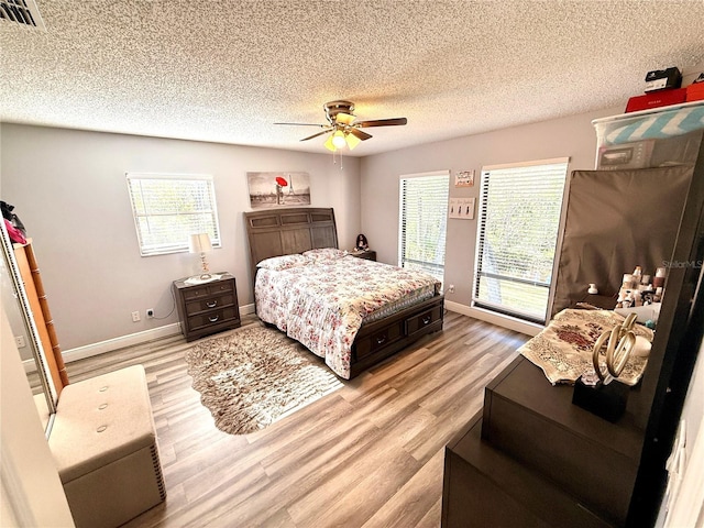 bedroom featuring ceiling fan, light hardwood / wood-style flooring, and a textured ceiling