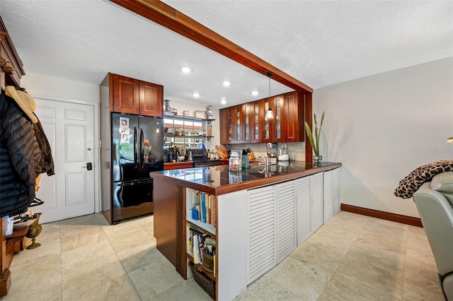 kitchen featuring hanging light fixtures, backsplash, kitchen peninsula, and black refrigerator