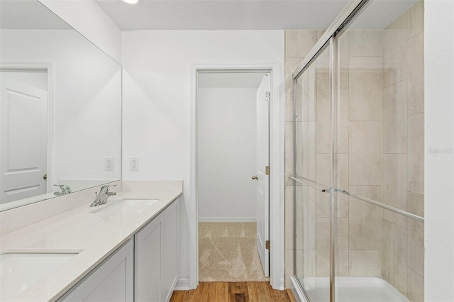 bathroom with hardwood / wood-style floors, walk in shower, and vanity