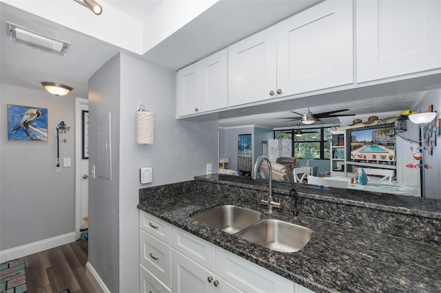 kitchen featuring white cabinetry, dark stone counters, and sink