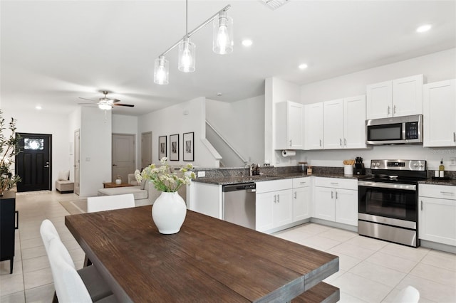 kitchen featuring ceiling fan, light tile patterned flooring, white cabinetry, hanging light fixtures, and stainless steel appliances