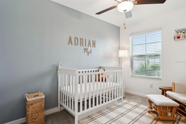 bedroom with ceiling fan, a nursery area, and carpet