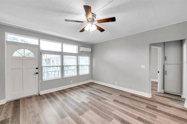 foyer featuring light hardwood / wood-style flooring, a wall unit AC, and ceiling fan