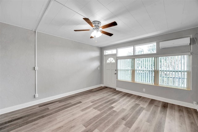 empty room featuring ceiling fan, a wall unit AC, and light wood-type flooring