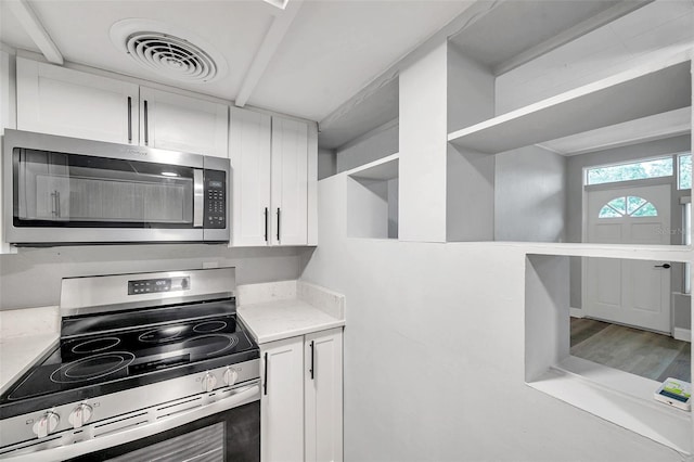 kitchen with white cabinetry, appliances with stainless steel finishes, and hardwood / wood-style floors