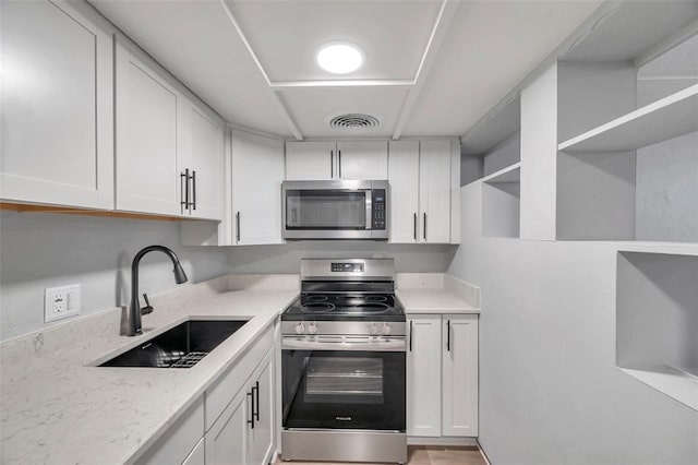 kitchen featuring white cabinetry, stainless steel appliances, light stone countertops, and sink