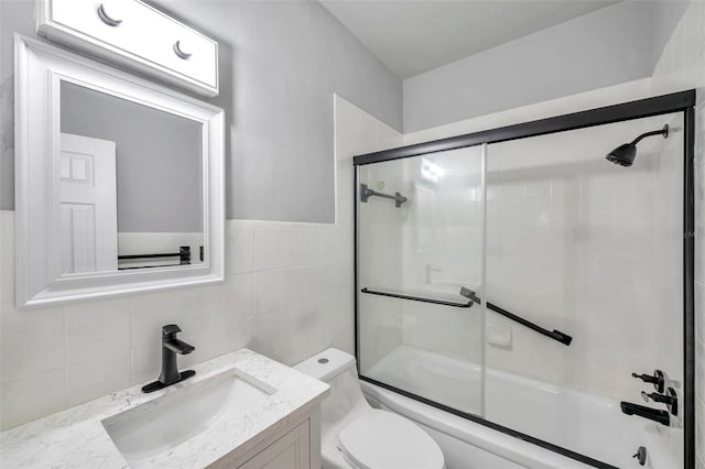 full bathroom featuring vanity, tile walls, enclosed tub / shower combo, and toilet