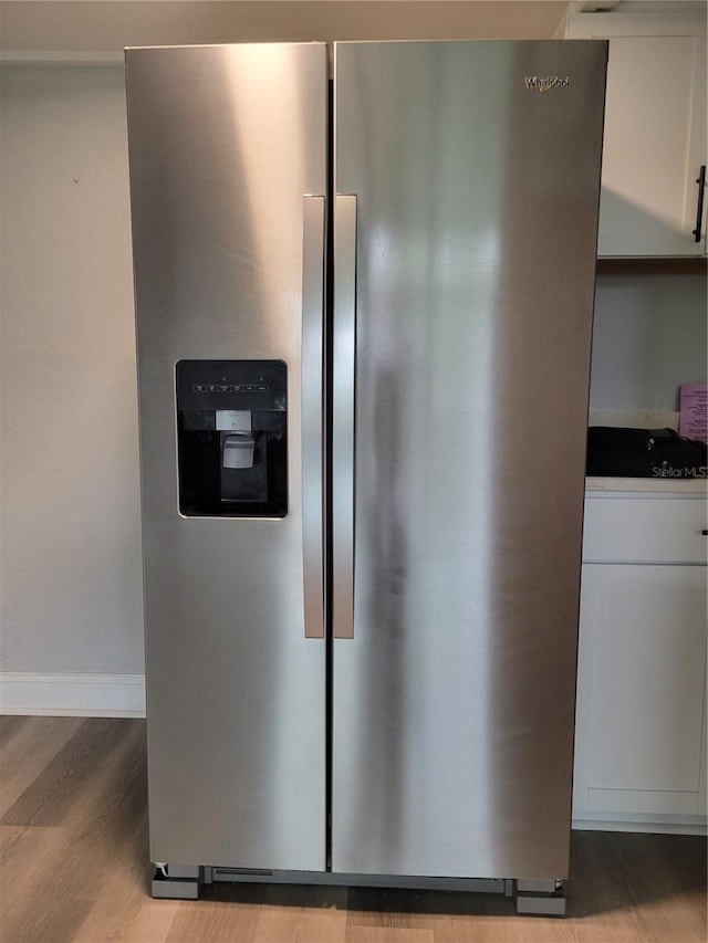 details with light hardwood / wood-style floors, white cabinets, and stainless steel refrigerator with ice dispenser