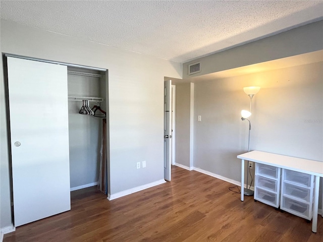 unfurnished bedroom featuring a closet, dark hardwood / wood-style floors, and a textured ceiling